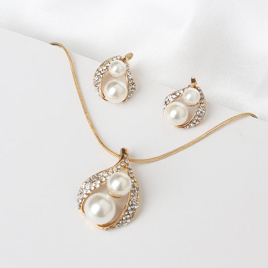 Gold-tone teardrop necklace and matching stud earrings set with white pearls and clear rhinestones, displayed on black. - Image 3