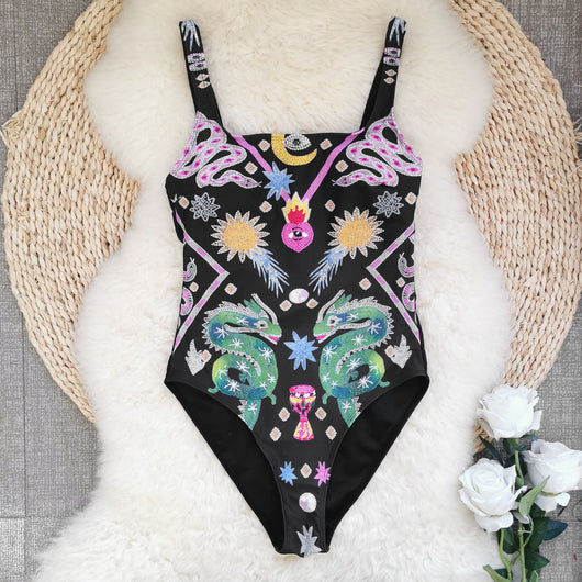 Black one-piece swimsuit for women featuring a vibrant multi-color print with dragons, suns, moons, and stars. - Image 4