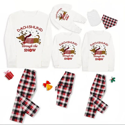 Family matching Christmas pajamas with white long-sleeve tops featuring a 'Dachshund through the snow' graphic and red and black plaid pants. Includes adult, ch