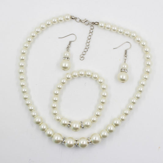Off-white pearl necklace, matching drop earrings, and bracelet set with rhinestone accents for bridal wear.