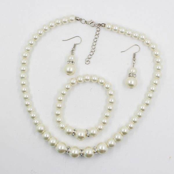 Off-white pearl necklace, matching drop earrings, and bracelet set with rhinestone accents for bridal wear.