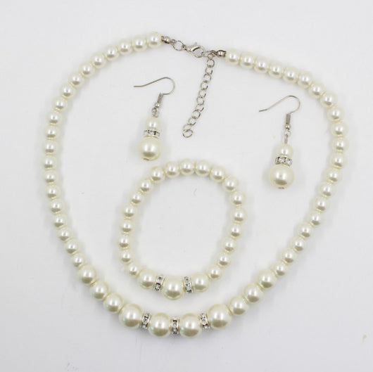 Off-white pearl necklace, matching drop earrings, and bracelet set with rhinestone accents for bridal wear.