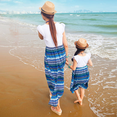 Family of four wearing matching white and blue striped outfits on a sunny beach, smiling at the camera. - Image 3