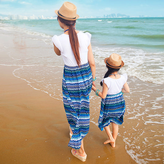 Family of four wearing matching white and blue striped outfits on a sunny beach, smiling at the camera. - Image 3