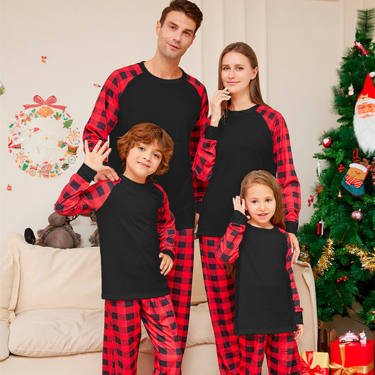 Woman wearing a black long-sleeve pajama top with red and black plaid raglan sleeves and matching plaid pants.