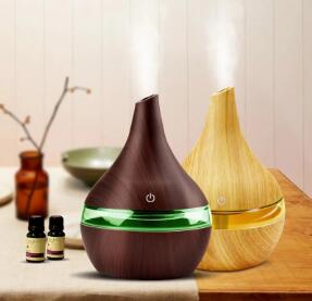 Teardrop-shaped humidifier with light wood grain finish and clear water tank, featuring a power button icon.