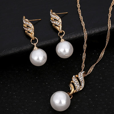 Gold-toned necklace and earring set with white faux pearls and clear rhinestones in a wavy design.
