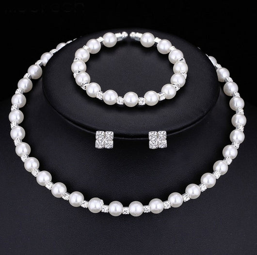 Bridal three-piece jewelry set with white pearls and clear rhinestones, including a necklace, bracelet, and square stud earrings.