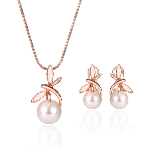 Rose gold-toned necklace and matching earrings set with white pearls and a delicate floral or leaf design.