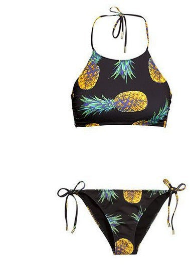 Black halter neck bikini top and tie-side bottoms with a vibrant yellow and green pineapple print.