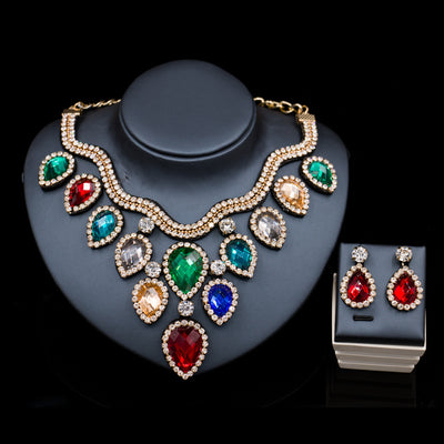 Colorful exaggerated bride necklace and earring set with large teardrop rhinestones on a dark display.