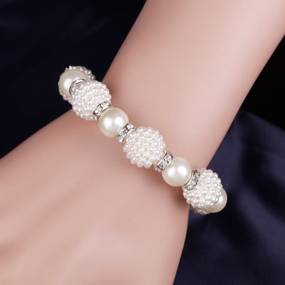 White faux pearl necklace, bracelet, and drop earrings set with rhinestone accents on a black display. - Image 3