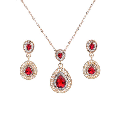Gold-toned necklace and matching drop earrings set with blue teardrop crystals and clear rhinestones, on a wooden box. - Image 4