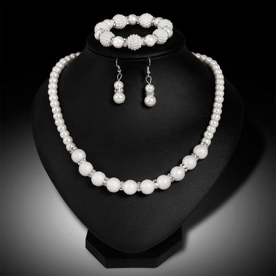 White faux pearl necklace, bracelet, and drop earrings set with rhinestone accents on a black display. - Image 6