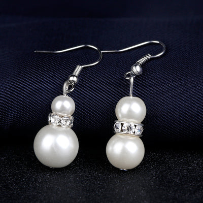White faux pearl necklace, bracelet, and drop earrings set with rhinestone accents on a black display. - Image 4