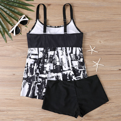 Woman in a black and white abstract print tankini top with black swim shorts on a sunny beach. - Image 11