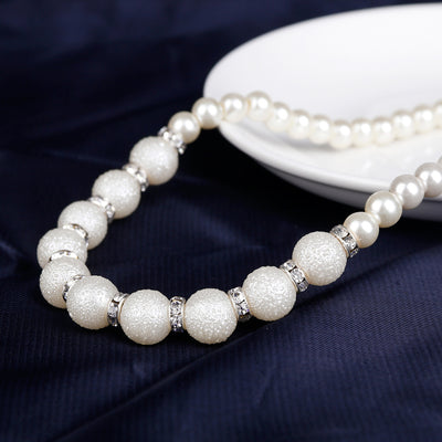 White faux pearl necklace, bracelet, and drop earrings set with rhinestone accents on a black display. - Image 5
