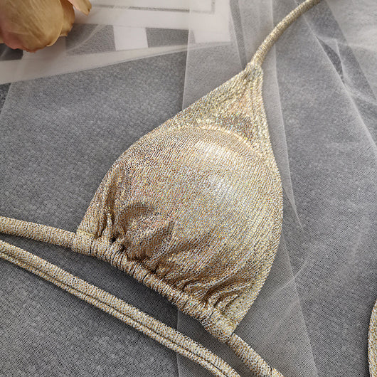 Woman wearing a shimmering gold one-piece swimsuit with a halter neck, crisscross straps, and stylish cut-out details. - Image 6