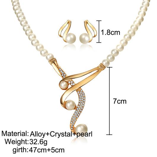Gold-toned pearl clavicle necklace and matching stud earrings set with rhinestone accents on a black display. - Image 3