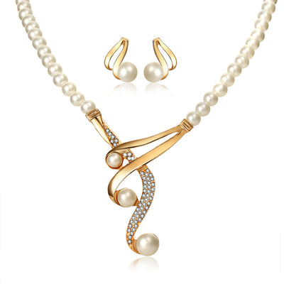 Gold-toned pearl clavicle necklace and matching stud earrings set with rhinestone accents on a black display. - Image 2