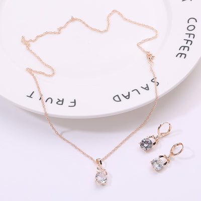 Rose gold-toned jewelry set with a necklace and matching dangle earrings, each featuring a round clear crystal. - Image 6