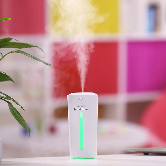 White mini USB ultrasonic humidifier with a green LED light strip, emitting mist, on a white surface. - Image 8