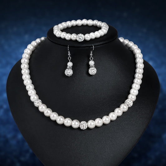 White faux pearl necklace, bracelet, and dangle earrings set with pave crystal beads on a black display.