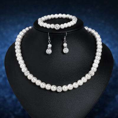 White faux pearl necklace, bracelet, and dangle earrings set with pave crystal beads on a black display.