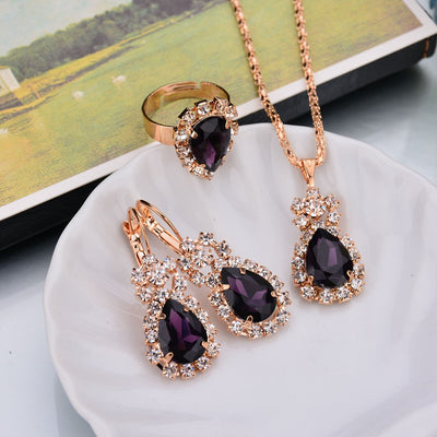 Rose gold-toned necklace, earrings, and ring set with large oval clear gemstones surrounded by smaller stones. - Image 19