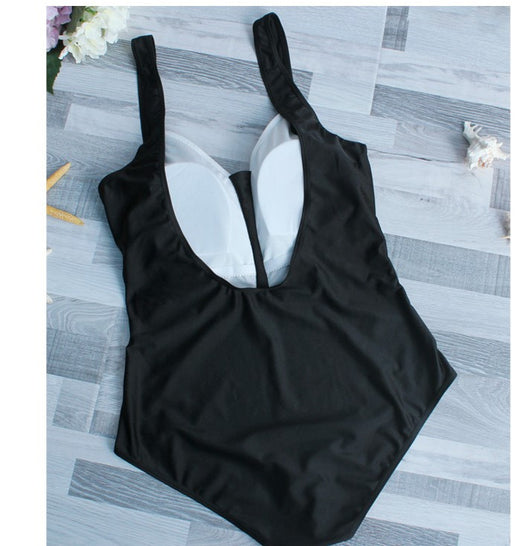Woman in black one-piece swimsuit with white trim, wide-brimmed hat, and striped tote bag on a sunny beach. - Image 3