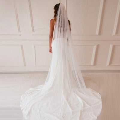 Mid-length white bridal veil with scattered pearl embellishments, flowing elegantly on a mannequin. - Image 2