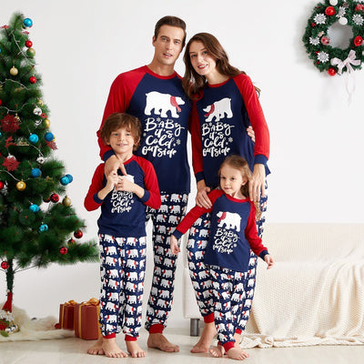 Child wearing dark blue and red Christmas pajamas with polar bear print and "Baby it's cold outside" text.