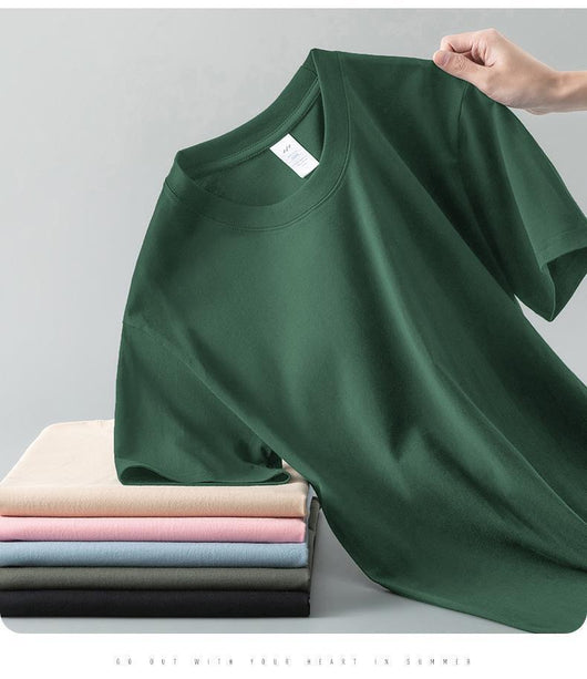 Light gray short-sleeve t-shirt with a round neck, held up to show its smooth fabric. A stack of folded t-shirts in various colors is visible in the background. - Image 26