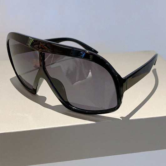 Oversized women's shield sunglasses with a tortoiseshell frame and brown-tinted lenses, held by a hand. - Image 12