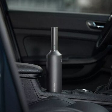 Dark gray cylindrical handheld vacuum cleaner in a car's cup holder, ready for quick interior cleaning. - Image 13
