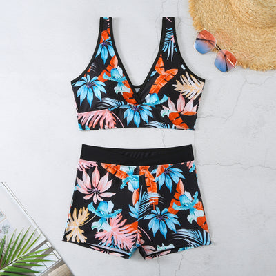Two-piece swimsuit with a black background and vibrant pink and purple tropical floral print. Features a V-neck crop top and high-waisted boxer shorts. - Image 12