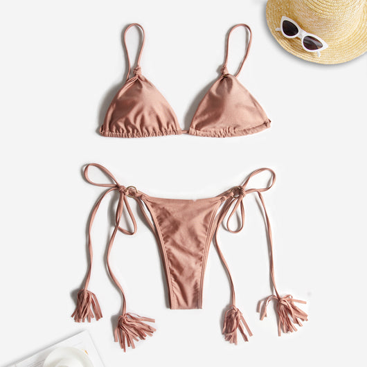 Black string bikini with wrap-around straps and gold-tone rings with tassels modeled on a beach. - Image 11