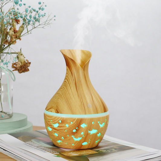 Dark wood grain humidifier shaped like a vase, with glowing green animal cutouts and mist emitting from the top.