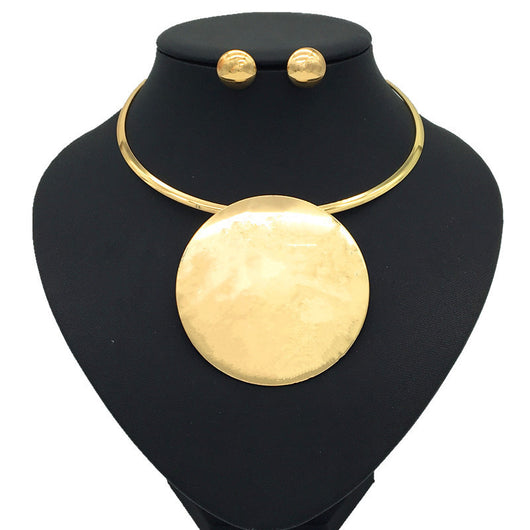 Silver-tone choker necklace with a large, flat circular pendant and matching round stud earrings on a black display.