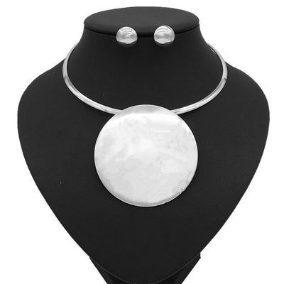 Silver-tone choker necklace with a large, flat circular pendant and matching round stud earrings on a black display. - Image 5