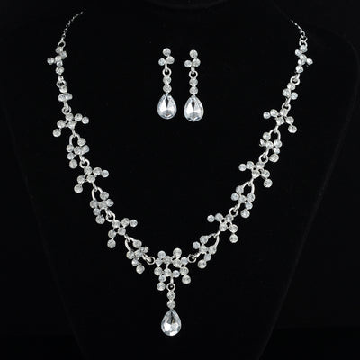 Silver-tone bridal jewelry set with a rhinestone floral necklace and matching teardrop dangle earrings on a black display. - Image 2