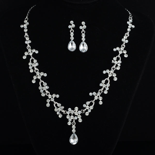 Silver-tone bridal jewelry set with a rhinestone floral necklace and matching teardrop dangle earrings on a black display.