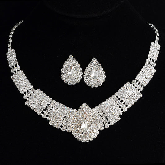 Sparkling bridal necklace and matching teardrop rhinestone earrings set on a black background.