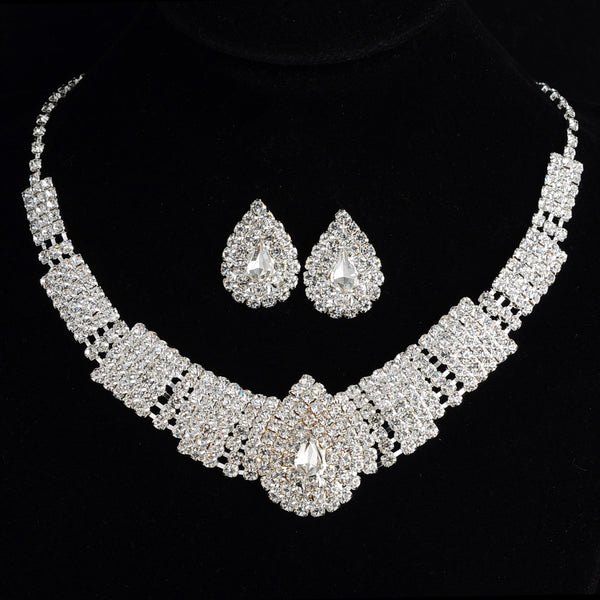 Sparkling bridal necklace and matching teardrop rhinestone earrings set on a black background.