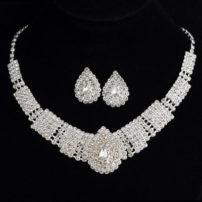 Sparkling bridal necklace and matching teardrop rhinestone earrings set on a black background.