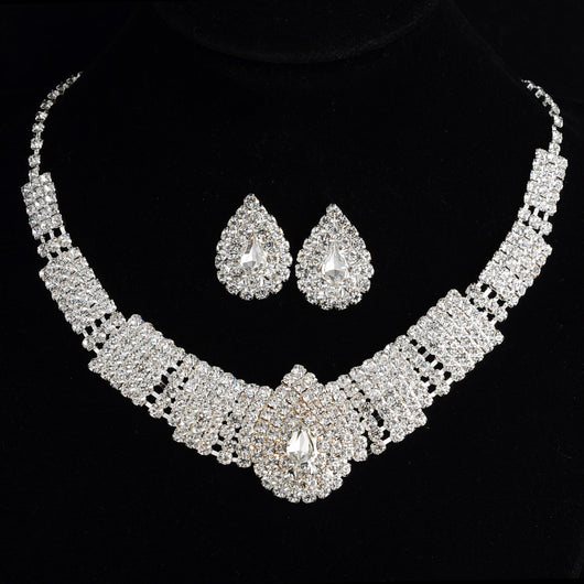 Sparkling bridal necklace and matching teardrop rhinestone earrings set on a black background.