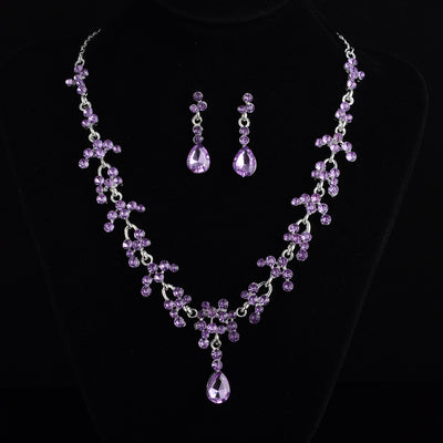 Silver-tone bridal jewelry set with a rhinestone floral necklace and matching teardrop dangle earrings on a black display. - Image 4