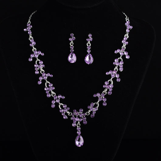 Silver-tone bridal jewelry set with a rhinestone floral necklace and matching teardrop dangle earrings on a black display. - Image 4