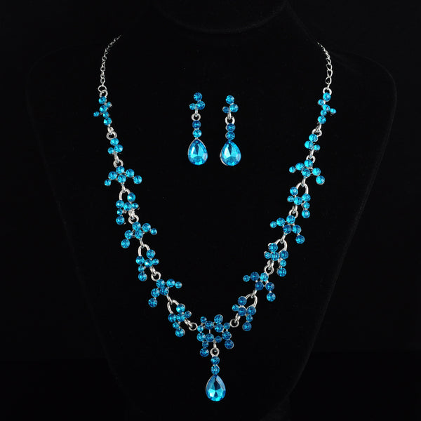 Silver-tone bridal jewelry set with a rhinestone floral necklace and matching teardrop dangle earrings on a black display. - Image 3