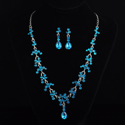 Silver-tone bridal jewelry set with a rhinestone floral necklace and matching teardrop dangle earrings on a black display. - Image 3